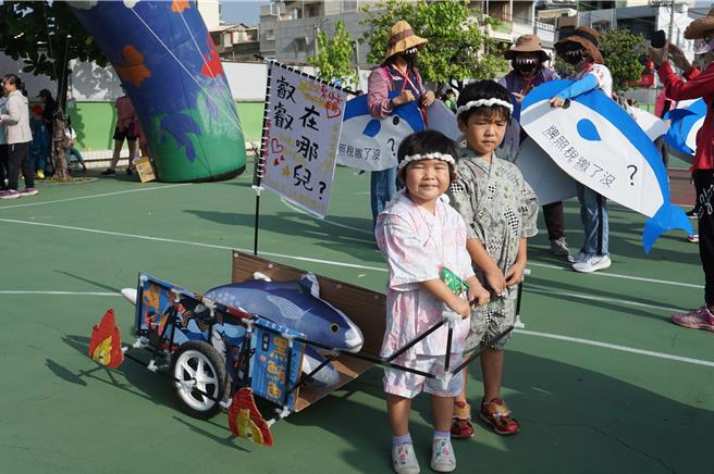 小朋友拉著兩條黑鮪魚的「百萬名車」。（羅琦文攝）