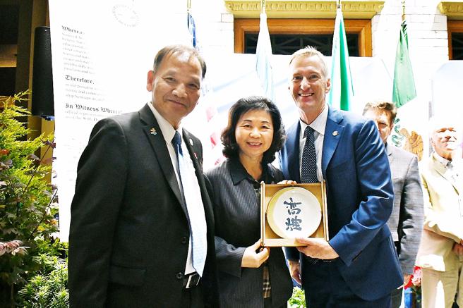 陳盈秀（中）於姊妹市接待會致贈高雄翻轉文字窯燒瓷盤予波特蘭市泰德惠勒市長（右）。（圖／高市行國處）