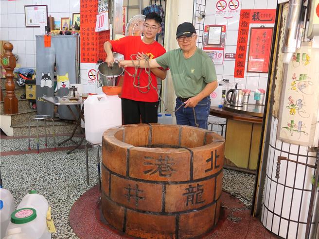 云林县北港朝天宫旁一家餐厅内有一口「龙井」，与朝天宫正殿水井同一水脉，10日餐厅老板王清坡（右）与孙子王颢铭（左）一起打水，让民眾拿回去制作午时水。（张朝欣摄）