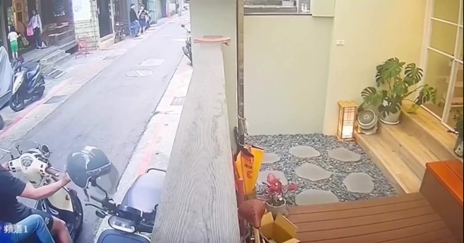 男子騎乘機車，載著一名女子經過理髮店外，竟伸手將掛在後照鏡上的安全帽偷走。（翻攝畫面）