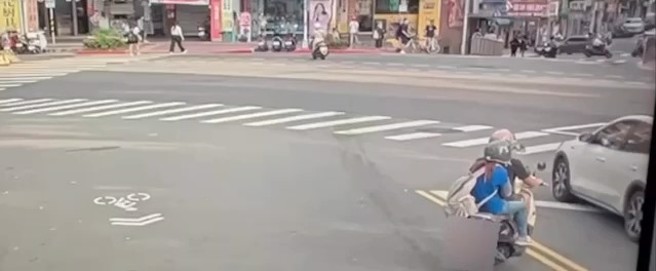 男子騎乘機車，載著一名女子經過理髮店外，竟伸手將掛在後照鏡上的安全帽偷走，並迅速將安全帽交給後座的女子戴上，隨即加速離去。（翻攝畫面）