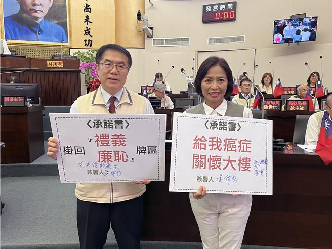 台南市議員王家貞拿出「掛回禮義廉恥牌匾」的承諾書，要求市長黃偉哲簽署；黃偉哲則在承諾書加上「及美德的題示」後簽名。（洪榮志攝）