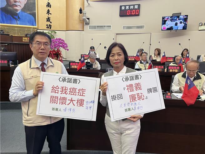 台南市议员王家贞拿出承诺书，请市长黄伟哲签名，承诺「给我癌症关怀大楼」；黄伟哲则加上「努力规画落实」等字后签名。（洪荣志摄）