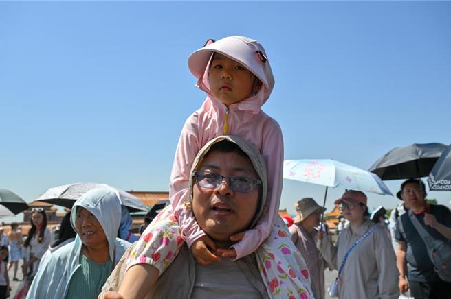 大陸北方大範圍高溫天氣12日陸續達到本輪過程巔峰。圖為小朋友與家長12日在高溫天氣下遊覽北京故宮。（中新社）