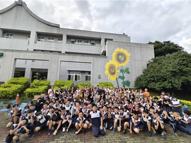 台中市新社国小行政大楼墙面，近来打造1座高约8公尺的「向阳而生」浮雕彩绘图，13日举行揭幕典礼，吸引了社区民眾与师生围观。（新社国小提供／张妍溱台中传真）