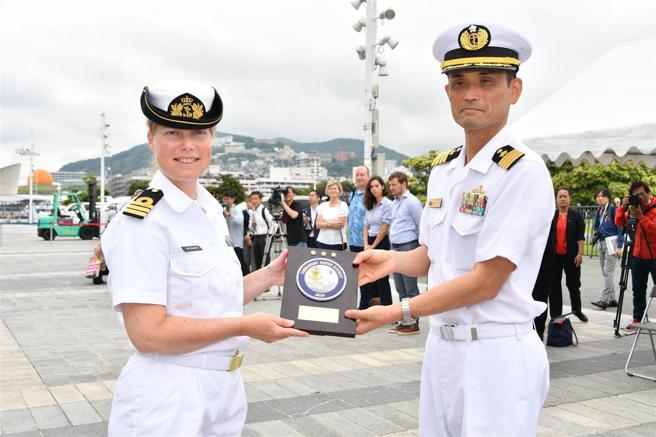  佐世保地方總監部代表（右）向「特羅普號」艦長布澤柯姆中校致贈紀念品，表達歡迎。（取自海自佐世保地方總監部「X」帳號）
