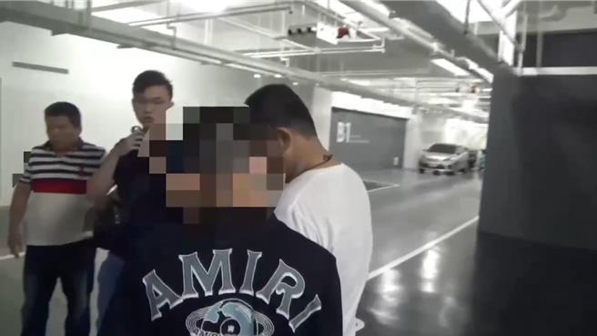 台南市林姓男子（黑衣背對者）躲入高級公寓大樓，將住處作為毒品分裝場販毒，遭警方在大樓下方停車場逮捕。（讀者提供／程炳璋台南傳真）