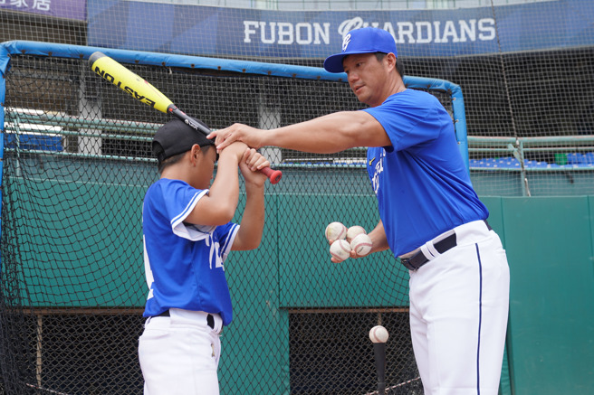 富邦悍將教練高國輝（右）指導小球員打擊。（富邦悍將提供）