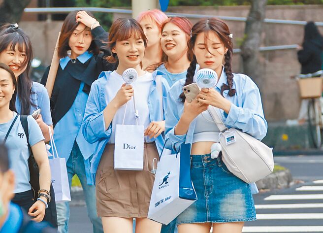 台湾各地22日持续受太平洋高压影响，各地高温炎热，今日桃园以北、中南部近山区及花东纵谷有机会接近36、37度高温。图为民眾拿小风扇散热。 （罗永铭摄）