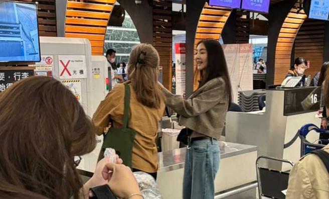 在等待行李过X光机检查时，吴速玲跟女友人聊天隐约露出平坦的小腹，好身材令人羡慕。（图／读者提供）