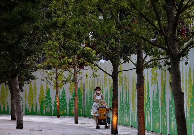 一名女性手推婴儿车走过东京街头（图／路透社）