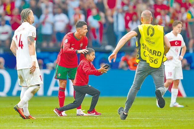 衝進場內跟C羅自拍的小球迷，躲避場邊保全圍捕。（美聯社）