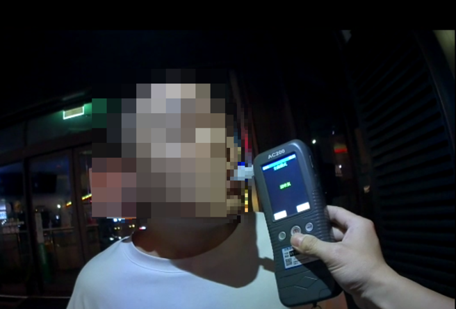 賴男吃完燒酒雞後，停等紅燈時違規使用手機，被巡邏員警攔查卻發現酒測超標，詢後被上銬依法移送偵辦。（翻攝畫面）
