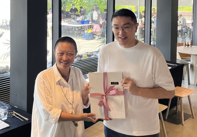 台湾生态饮食设计中心发起人吴秀娟代表致赠「海洋国宴永续食谱」予谢国梁市长。（图／政大社科院提供）