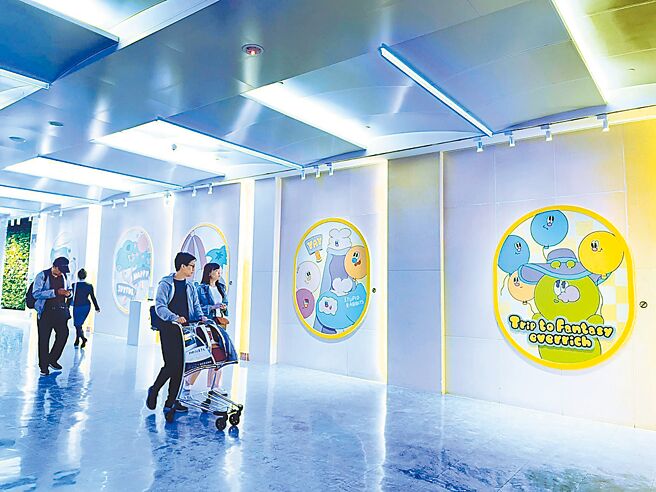 人氣插畫家KINGJUN特別為了昇恆昌免稅商店獨家設計圖素，並在松山、桃園及台中三大機場文化藝廊設展；圖為旅人經過桃園機場A區展區觀展照片。圖／昇恆昌免稅商店提供