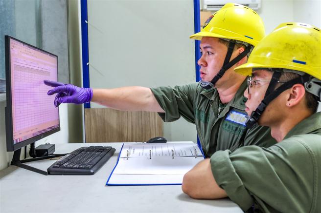 　梁俊贤（左）与同事一同查看马力机负载测试，确保动力系统稳定。（记者杨乔琳摄）