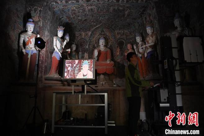 2024年6月，甘肃敦煌莫高窟内，敦煌研究院文物数字化研究所工作人员进行敦煌壁画数字化採集工作。（中新网）