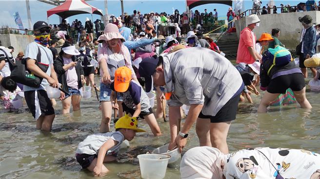 挖文蛤区挤满人，岸上还有很多人排队等着下水。（宝智华摄）