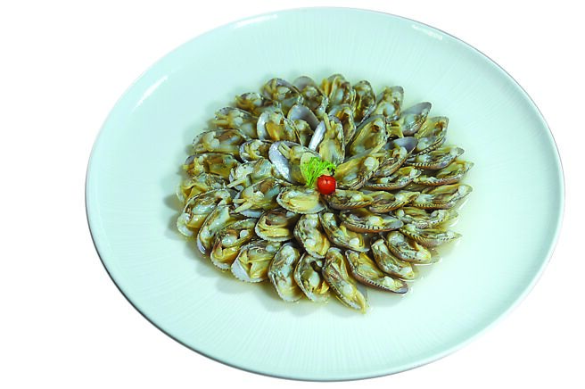 〈魚露花甲〉是將花甲加入蒜苗輕輕汆燙後，以魚露、九層塔碎和蒜末調製成的醬汁提味，清爽開胃。圖／姚舜