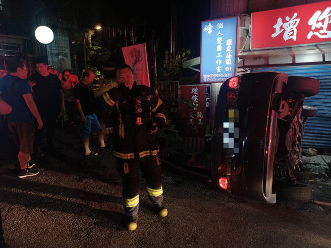 轎車撞擊旁邊文具店鐵捲門後側翻，駕駛由消防隊救出送醫。（翻攝畫面）