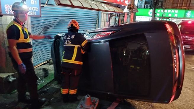 轎車撞擊旁邊文具店鐵捲門後側翻，駕駛由消防隊救出送醫。（翻攝畫面）
