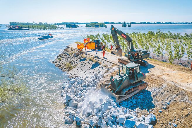 大陸洪災造成湖南岳陽的洞庭湖潰堤，應急部門出動武警民兵和各類機械，搶險修復。（新華社）