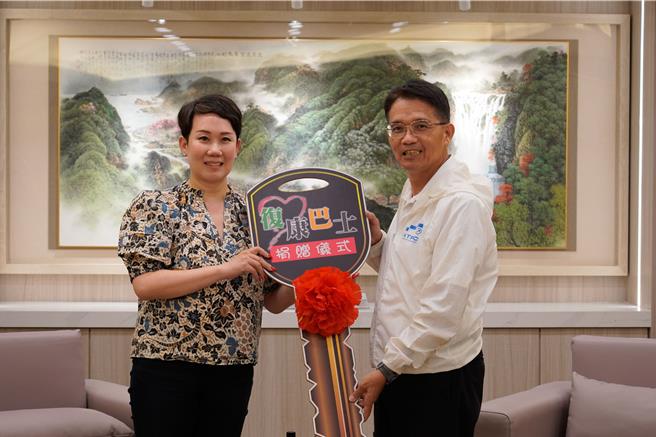 吳瑤華（左）捐贈第二輛復康巴士給新北市政府，由新北市政府秘書長邱敬斌代表接受。（新北市社會局提供）