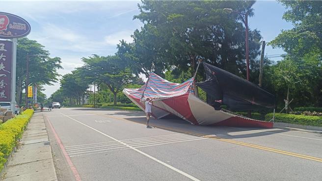 金門家樂福賣場前方臨時搭建的夜市，今日下午突遭一陣怪風侵襲，造成其中攤位一頂20尺的大帳篷直接被吹翻，甚至還飛到伯玉路上占據整個對向車道，嚇壞路過民眾。(圖／民眾提供)