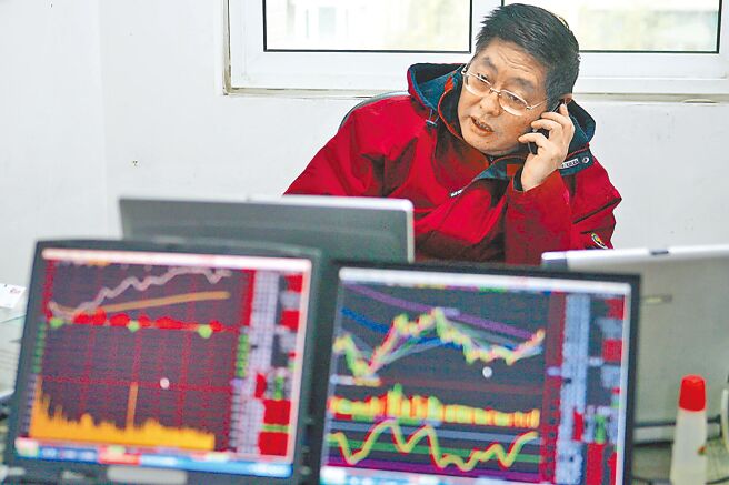 為打擊做空亂象，維護市場穩定，大陸證監會10日宣布，依法批准中證金融公司暫停轉融券業務的申請，自11日起實施。圖為民眾一邊用手機打電話，一邊看股市行情。（中新社）