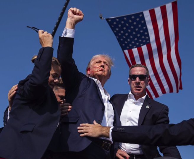 川普遇刺受伤，脸上带血，握拳并向支持群眾高喊「战斗」。 （美联社）