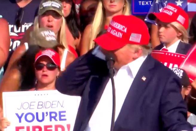 槍手射殺川普的瞬間，正在演說的川普覺得右耳有異樣，一摸發現血跡，立即蹲下躲到講台下。至於其右耳的傷勢，川普陣營說是子彈擦傷，安全特勤人員則說是被擊碎的玻璃碎片劃傷。（圖／路透）