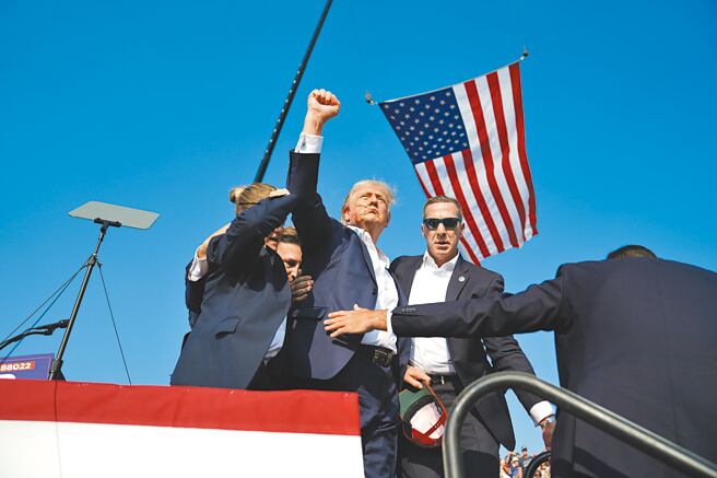 美國前總統川普13日在賓州巴特勒郡（Butler County）出席競選活動時遇刺，現場傳出多聲槍聲，多名特勤人員衝上台掩護川普，川普右耳受傷、臉部染血，仍一路振臂揮拳喊口號。（美聯社）