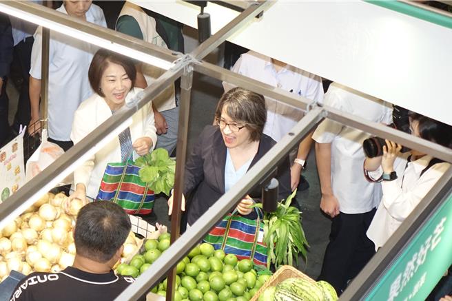 副总统萧美琴提着茄芷袋买了酪梨和苦瓜，摊商附赠一个丝瓜。（罗琦文摄）