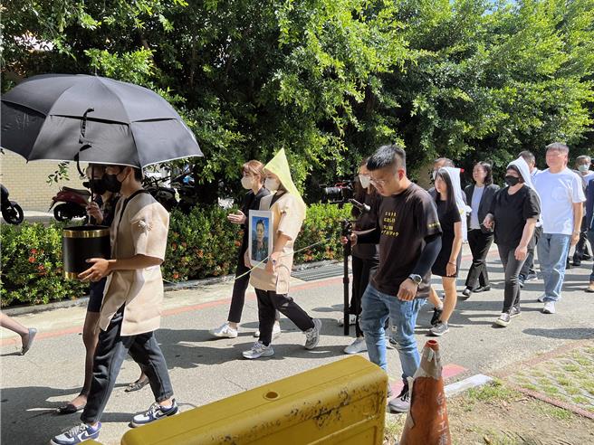 南市区渔会理事长林士杰被枪击身亡，家属17日上午举行家祭后，林士杰女儿市议员林依婷神情哀戚地捧着父亲的照片发引安葬。（洪荣志摄）