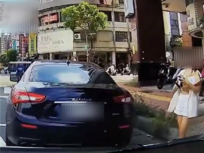 高雄一輛黑色馬莎拉蒂轎車停於路口，後發車輛狂按喇叭至女駕駛上車離開，警方說雙方都已違規可開罰。（翻攝自「社會事新聞影音」／任義宇高雄傳真）