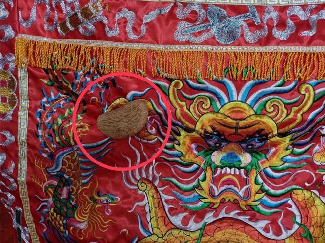 彰化市南安寺寺方人員17日擲筊請示慶典事宜，其中1個筊杯落地彈跳後，不偏不倚彈至神桌的龍紋桌裙卡住，消息傳開後信眾嘖嘖稱奇。（翻攝彰化南安寺臉書／孫英哲彰化傳真）