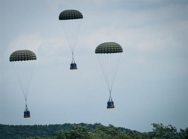  美韓C-130J運輸機空投物資，在空中開出朵朵傘花，精準落在目標區。（取自DVIDS網站）