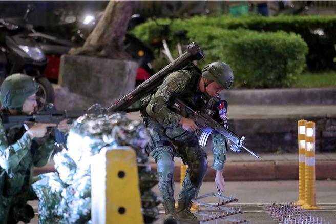 1名官兵揹著紅隼火箭發射筒，拉開雞爪釘，設置道路阻絕設施。（黃世麒攝）