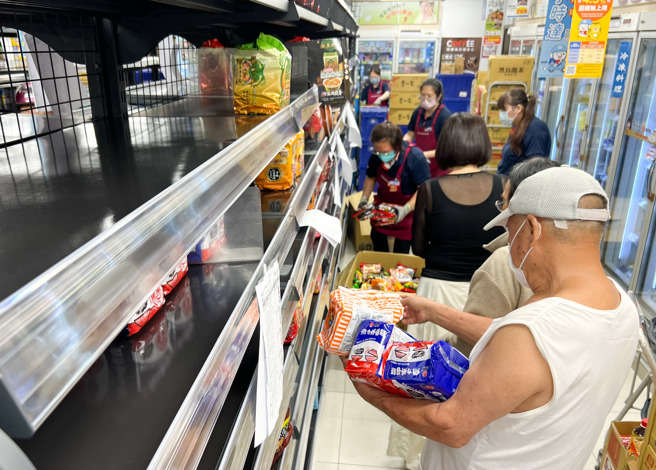 颱風來襲，賣場人員在泡麵架上忙著補貨，一旁民眾搶著購買。（資料照片/陳俊吉攝）