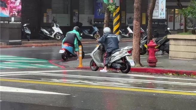 基隆市25日上午陣風高達12級，機車騎士被強風逼得只能停在路邊勉力維持不被吹倒。（張志康攝）