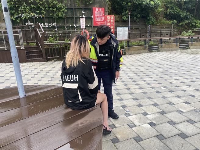 女子负气离家夸坐湍急大圳旁，员警即时发现并上前救援安抚。(平镇分局提供／廖姮玥传真）