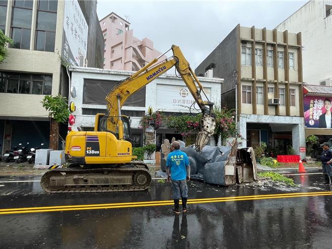 花蓮軒轅路上一間咖啡店樓頂的裝置藝術「巨型摩艾像」被強風吹落，躺倒馬路中央。一早動用重機械移除。（里長張東耀提供）