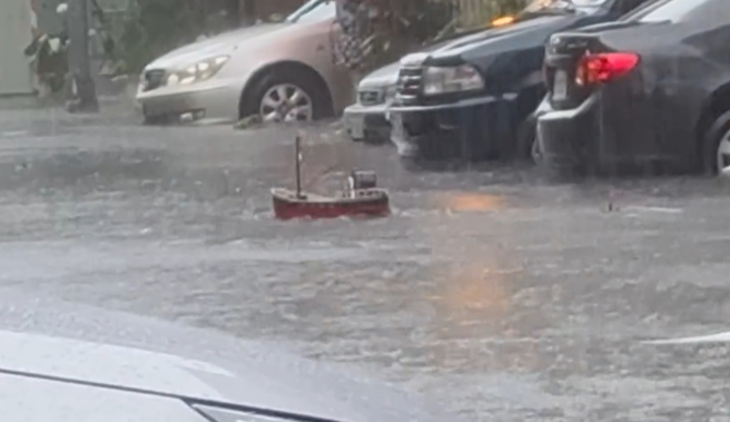 馬路淹水居然出現遙控船，原來是住戶苦中作樂，把家中遙控船拿出來玩。（翻攝爆料公社）