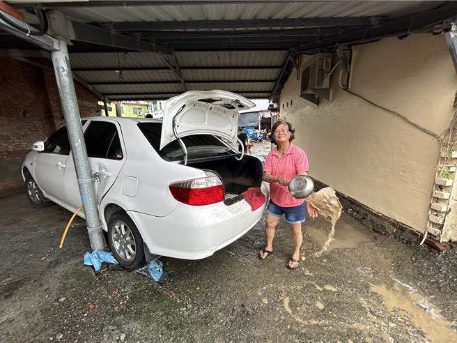 強颱凱米肆虐，屏東縣高樹鄉建興村慘遭水淹，村民26日無奈地從後車箱把積水一杓一杓舀出來，苦笑幸好大水把汽車沖轉90度後撞到柱子擋住，不然連要去哪裡找汽車也不知道。（謝佳潾攝）