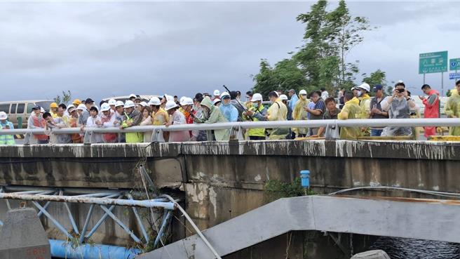 行政院長卓榮泰（左七紅背心透明雨衣者）與台南市長黃偉哲（左八）站在八掌溪橋上，視察溢堤破口。（程炳璋攝）