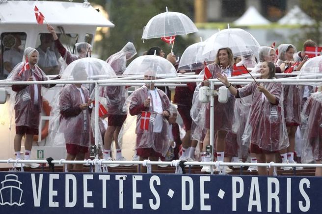 開幕典禮天候不佳，丹麥代表團撐雨傘進場。（美聯社）