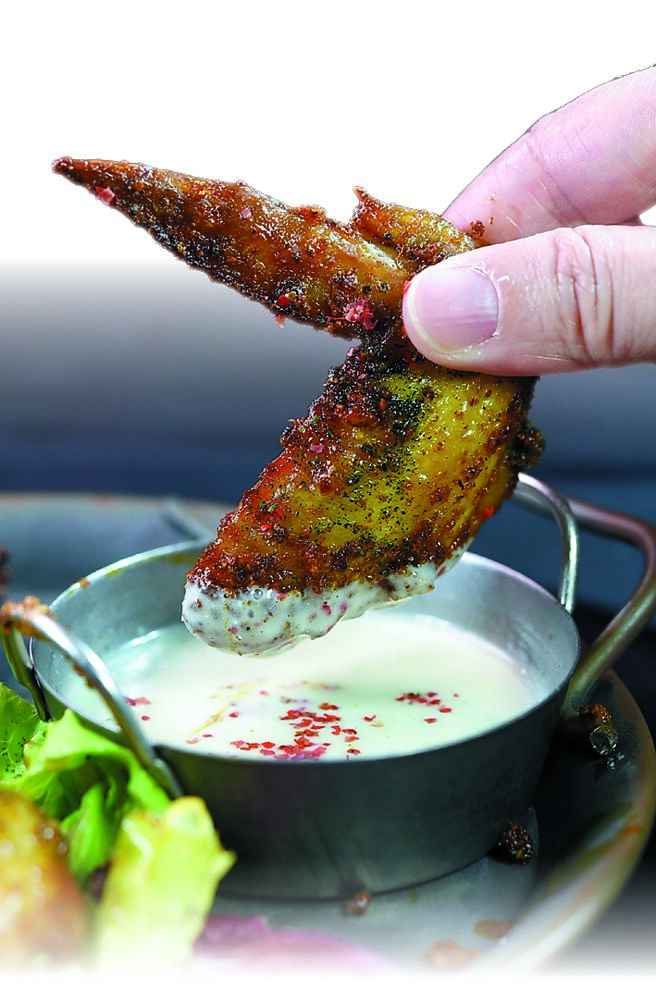 品嘗〈香料烤雞翅佐藍紋乳酪醬〉可以沾附藍紋乳酪製作的醬汁。圖／姚舜