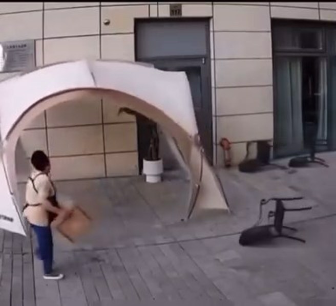 戶外咖啡店突然遇到強風，店員不畏強風在收拾物品。（翻攝爆廢一公社）