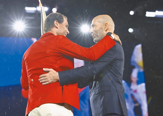 法國足球巨星席丹（右）在巴黎奧運開幕式主舞台將聖火交棒給納達爾，兩人惺惺相惜。（美聯社）