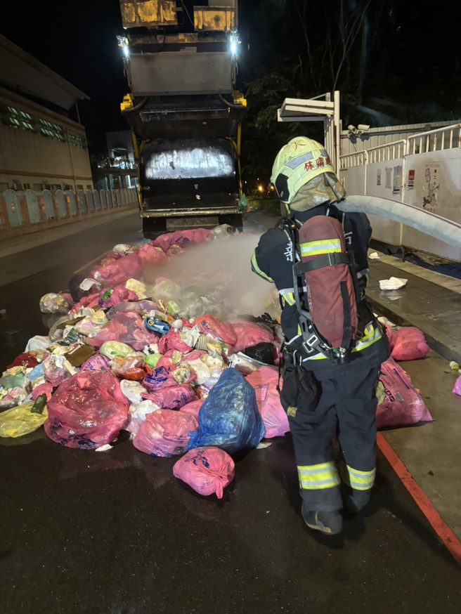 新北市板桥区一辆垃圾车后斗的垃圾突然冒烟，消防队到场洒水灌救。（翻摄画面）